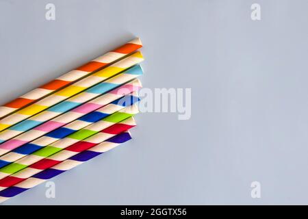 Disposable colorful striped paper cocktail sticks lie chaotically on light blue background. Eco friendly paper drinking straws. It's the choice for re Stock Photo