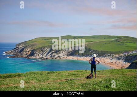middle-aged woman with straw hat resting in front of the  beach of  el Sable de Tagle, Suances, Cantabria, Spain, Europe Stock Photo