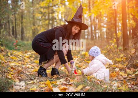 black witch woman with little toddler bunny in the autumn forest. halloween celebration, costume party. Stock Photo