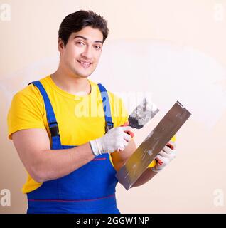 The young contractor employee applying plaster on wall Stock Photo