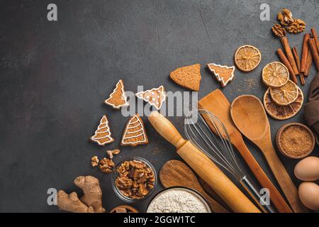 Ginger cookies, ingredients and kitchen utensils on a dark background. Stock Photo