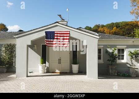 House decorated with american flag with landscape and blue sky with clouds in background Stock Photo