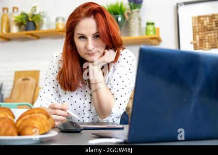 Young artist woman sketch on digital tablet on creative table at home kitchen Stock Photo