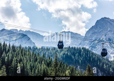 Two cabs of the cableway and skiers on the slope of the mountain Chopok south side on a sunny day in the ski Stock Photo