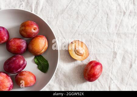 Victoria plums in a grey bowl over beige linen tablecloth. Stock Photo