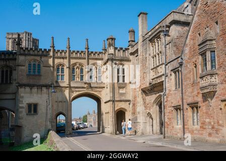 Wells UK architecture, view in summer of people entering the medieval arched gatehouse that separates St Andrew Street from Cathedral Green, Wells. Stock Photo
