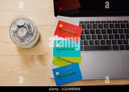 Credit cards placed on laptop with a jar of coins placed beside. Stock Photo