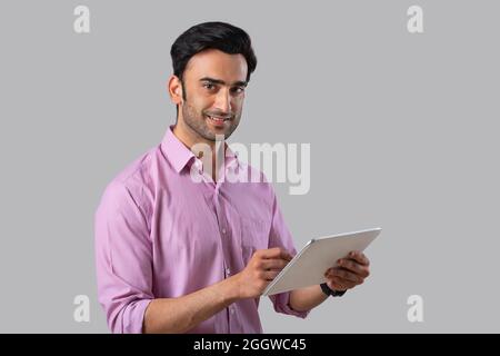 An employee in formal clothing holding a digital tablet,looking at the camera. Stock Photo