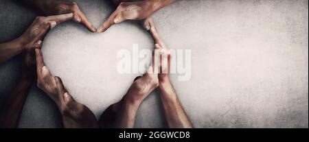 Different people unite for a common purpose as diverse person hands join together and create heart shape, isolated on grey wall background with copy s Stock Photo