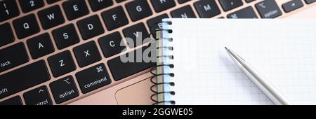 Spiral notepad and ballpoint pen lying on laptop keyboard closeup Stock Photo
