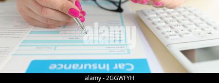 Woman holding toy car in her hands and filling out insurance form closeup Stock Photo