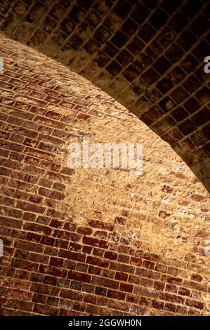 Red brick walls meet in a curve, with discolouration of the bricks due to moisture Stock Photo