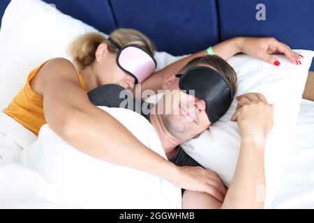 Hugging man and woman with sleep mask sleeping bed Stock Photo