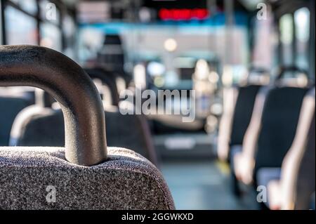 Focus on headrest of empty metro bus with the aisle to the front ...