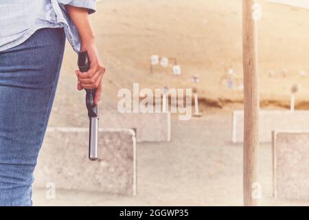 Gun in the hands of a girl, close-up arms. Stock Photo