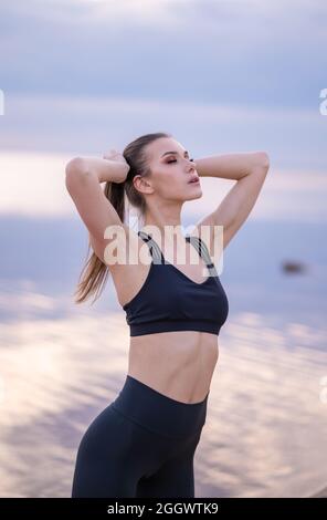  conceptual photo of a young girl stretching on the seashore at sunset
