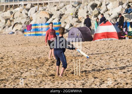 Young boys on a staycation holiday and enjoying a game of cricket on Fistral Beach in Newquay in Cornwall. Stock Photo