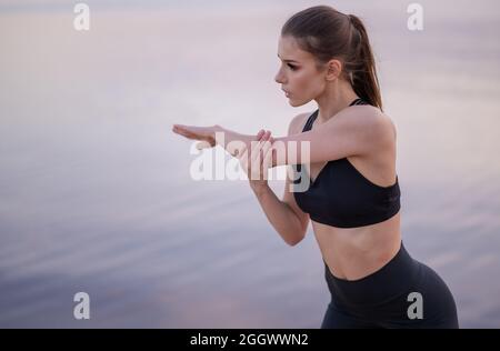  conceptual photo of a young girl stretching on the seashore at sunset