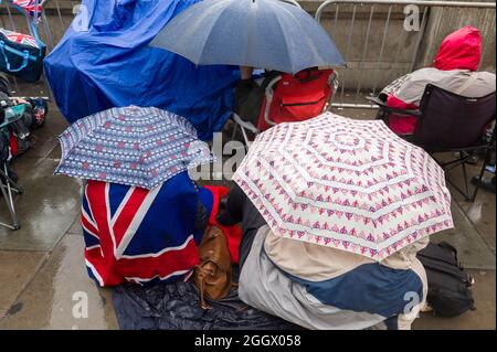 Spectators waiting in the rain for The Thames Diamond Jubilee Pageant to pass the South Bank, London. The Pageant was made up of hundreds of boats that sailed from Battersea Bridge to Tower Bridge to celebrate Queen Elizabeth II's 60 years on the throne. Millions of people lined the banks of the Thames to watch the spectacle.  South Bank, London, UK.  3 Jun 2012 Stock Photo