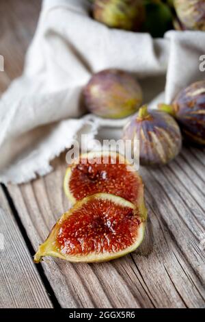 fig open in two parts next to other whole figs on wooden table. Stock Photo