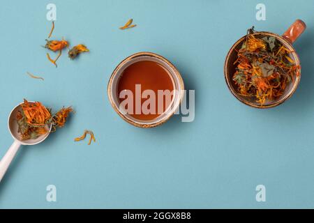 Calendula dried herbs in orange craft cup with honey on blue background Stock Photo