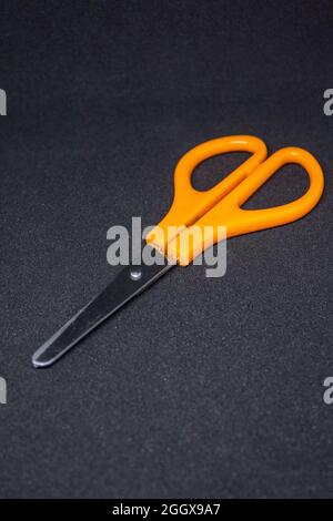 scissors with orange plastic handles isolated on black background Stock Photo