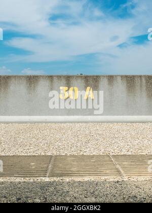 Stencilled yellow paint number 30A on a concrete sea wall Stock Photo