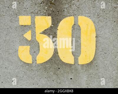 Stencilled yellow paint number 30 on a concrete sea wall Stock Photo