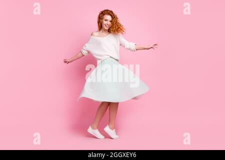 Full length body size photo of red hair girl laughing in skirt dancing in spring spinning isolated on pastel pink color background Stock Photo