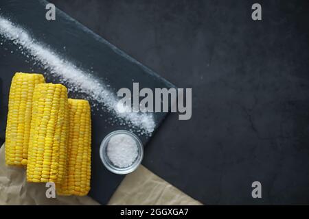 Freshly made fragrant ear of corn with salt. Farm snack fresh corn. Healthy breakfast and healthy lifestyle concept. Stock Photo