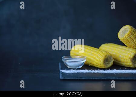 Freshly made fragrant ear of corn with salt. Farm snack fresh corn. Healthy breakfast and healthy lifestyle concept. Stock Photo