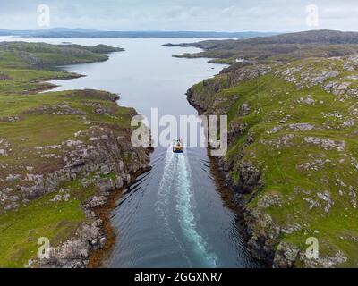 Aerial view from drone of fishing boat sailing between channel between Little Bernera and Great Bernera on  Isle of Lewis, Outer Hebrides, Scotland, U Stock Photo