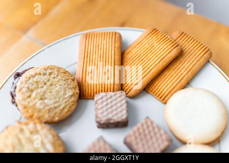 Assortment of baked snacks of gourmet chocolate cookies with wafers and sweet biscuit with filling on white plate macro closeup Stock Photo