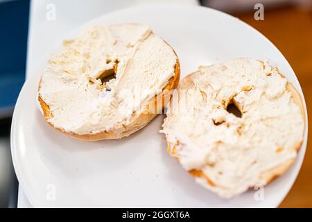 Bagel bread toasted slices closeup on white plate topped with cream cheese plain as breakfast brunch food Stock Photo