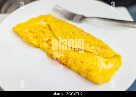 Fresh hot cheese egg omelette on white plate cooked folded traditional for morning breakfast closeup and fork Stock Photo