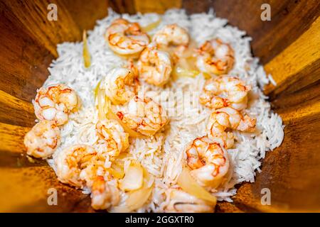 Macro closeup of homemade basmati rice and cooked whole large king jumbo Argentinian fried shrimp seafood with sweet onion slices in wooden bowl plate Stock Photo