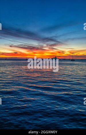 Silhouettes of boats at colorful sunset twilight blue hour with landscape view on blue cloudy sky reflection in water by Mallory Square of Key West, F Stock Photo