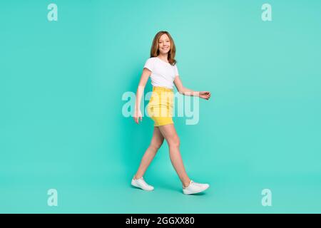 Full length body size photo smiling schoolgirl walking forward isolated vivid teal color background Stock Photo