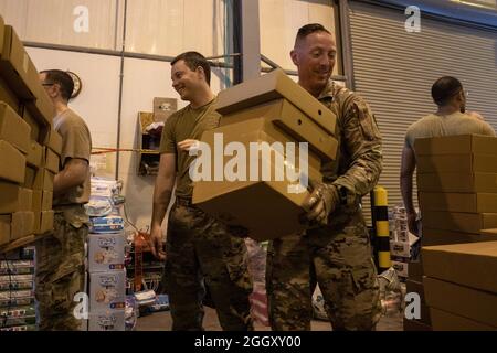 U.S. Army Chief Warrant Officer 4 Aaron Baldwin (right), the maintanance advisor for DSCCMO-A US LOG, and Air Force Capt Nathan Kinghorn, a JAG Officer for the 379th JAG Wing Office (left), move boxes of food for qualified evacuees at Al Udeid Air Base, Qatar, Aug. 25, 2021. Both Baldwin and Kinghorn were volunteering their time, with Baldwin saying 'We just need to help.' (U.S. Army photo by Spc. Maximilian Huth,  U.S. Army Central Public Affairs) Stock Photo