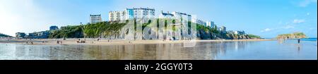 A panoramic view of The South Beach at Tenby in Wales, UK, featuring colourful buildings along The Esplanade on the cliff above. Stock Photo