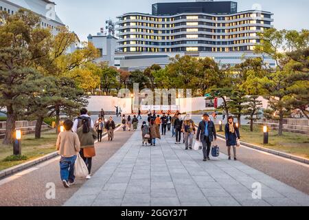 Osaka, Japan - April 13, 2019: Crowded castle grounds in evening night and many people walking on street road in downtown Stock Photo