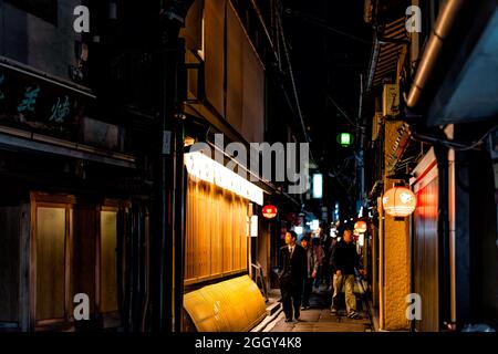 Kyoto, Japan - April 16, 2019: Back street famous narrow Pontocho alley downtown district at night by izakaya restaurants at night with salaryman Stock Photo
