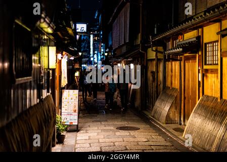Kyoto, Japan - April 16, 2019: Narrow alley street in Gion district at night with people and illuminated restaurant building with menu Stock Photo