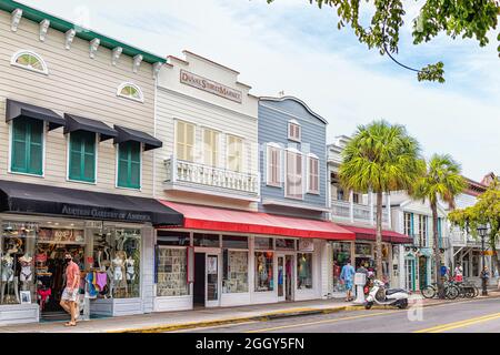 Key West, USA - January 25, 2021: Duval Street road sidewalk in Florida keys city with people walking by souvenir gift stores, art gallery shops by pa Stock Photo