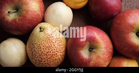 Juicy fruits on a old wooden table. Apples, pears, plums, apricots, close up. Stock Photo