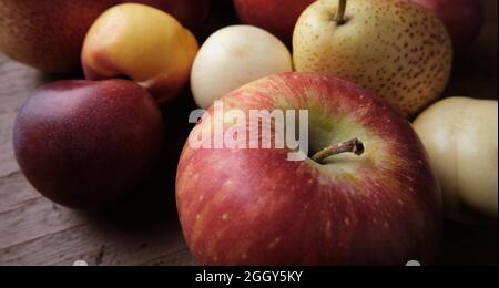 Juicy fruits on a old wooden table. Apples, pears, plums, apricots, close up. Stock Photo
