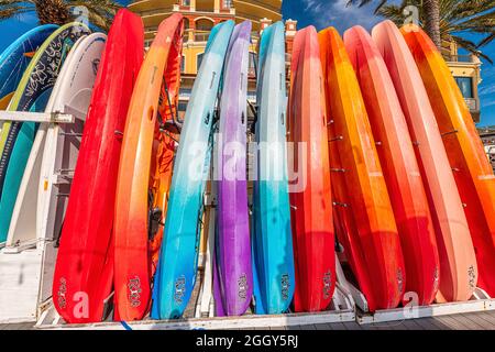 Destin, USA - January 13, 2021: Row stack of many colorful red blue purple yellow kayak boats in Florida resort city town village with Tribe sign on H Stock Photo