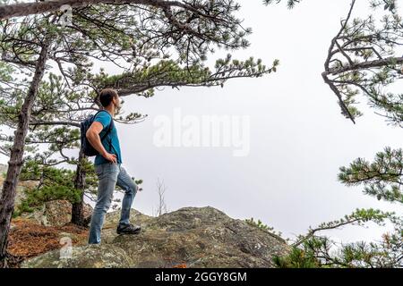 Blue Ridge mountains in fall season with green trees on mountain peak and one young man hiker on cliff at Cedar Cliffs overlook in Virginia looking at Stock Photo