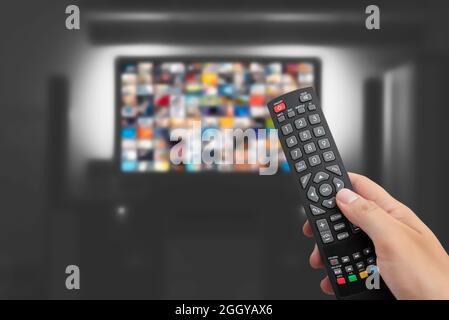 Video on demand, TV streaming, multimedia. Hand holding remote control Stock Photo