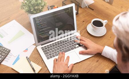 Programmer working on code in office. Man working on laptop. Stock Photo